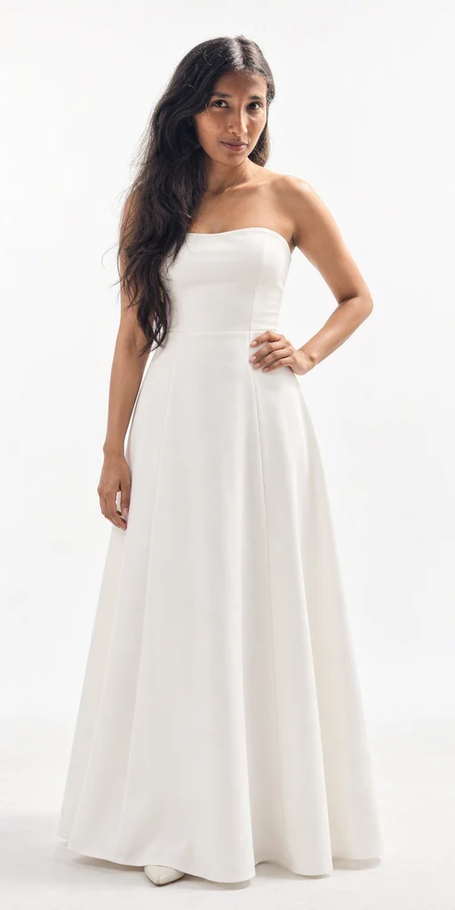 Front view of Harshitha in a plain white floor-length dress. Approved AI visualization created from her actual reference photos.